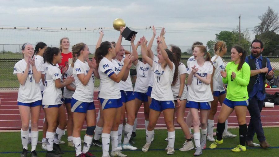 The+Knights+and+their+first-year+coach+Barney+Guerra+huddle+around+their+new+favorite+shared+possession%3A+the+bi-district+championship+trophy.