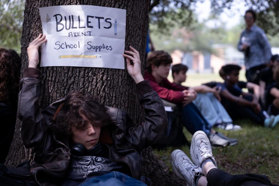 TAKING ACTION: Junior Zephan Mayeda leans against a tree during the walkout holding a sign reading “bullets aren’t school supplies.” He participated in the walkout to protest against the lack of gun protection in the US and draw attention to the statewide protest. 

“Children are dying due to government’s apathy and corporate lobbying against any action of any kind,” Mayeda said. 

Mayeda was disappointed in the lack of organization that came with the protest, but still participated. 

“Better something than nothing,” he said. 

Mayeda offered what he would love to see at the walkout.  

“I would have loved to see marching, chants, speeches, lists of phone numbers to call senators, names pictures and birthdays of the victims, flyers promoting the protest days weeks or months even in advance, mass absences, an actual walkout for those who can’t not go to school that isn’t just 20 mins of sitting,” Mayeda said.

Although he was underwhelmed, Mayeda appreciated the symbolism. 

“I think it held some importance in regards to symbolic gestures,” Mayeda said. 

Reporting by Kate Boyle. Photo by Gergő Major.