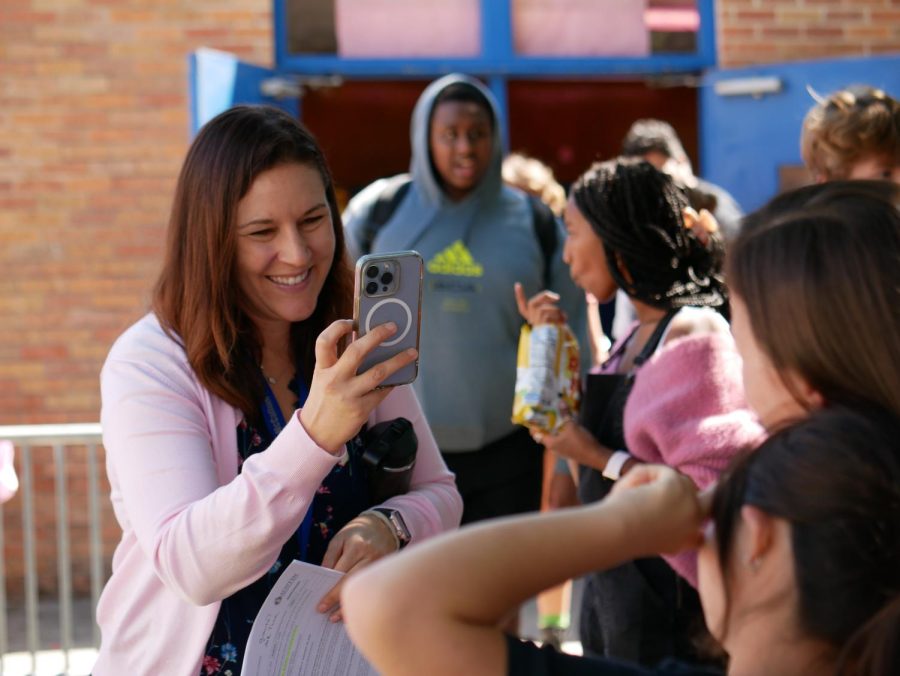 Veteran photojournalist Nicole Griffith snaps a  candid shot of college and career counselor Camille Nix and senior Sabine Collins during Pink Week activities on Tuesday in the courtyard across the cafeteria.