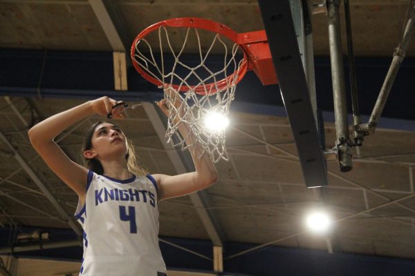 Junior small forward Esme Barraz cuts down the net after the Knights completed their perfect district season with a victory over the Ann Richards Stars at home on Feb. 7.