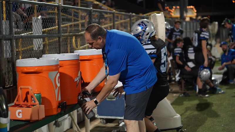 Principal Andy Baxa utilizes the ice-cold water jugs provided by House Park at the varsity football game v.s. Lehman