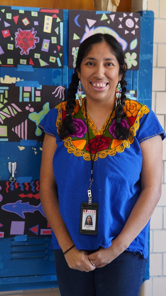 HASTA LA RAÍZ: Nancy Morelos, McCallum’s new AP clerk, poses while wearing a lapis lazuli Mexican blouse of indigenous origin with a vibrant bouquet of flowers splayed across its ruffles for Hispanic Heritage Month. According to Morelos, simulacra of her vivid lapis lazulis are often available in the United States, but they’re inauthentic, shoddy replicas of cultures that have fought to express their joy for centuries. Hers is handmade, a bestowal from her sister, who obtained it in Cabo San Lucas. By her own account, Morelos is Mexican.

“I was born in Celaya Guanajuato. I was raised here, but I’ve always been connected to my Mexican, and immigrant heritage,” Morelos said. “It [the lapis lazuli] was a gift from my sister from her recent visit to Mexico. The one I wore is traditional in the sense that it’s handmade. It’s something in Mexican culture that we’ve lost to an extent, but we’re trying to preserve it. My family has discovered that we’re part Chichimeca, through my mother, and Ayahuasca, from Veracruz, where my dad comes from. My sister did our DNA lineage, and we’re pretty much all indigenous. Once we learned that, I felt a very close connection to my people, our history, a history that we’ve unfortunately had to leave behind for opportunities in the States. When I wear those earrings, and those braids, and that garment, I’m doing it to express who I am and to honor the people that made that garment.” 

Morelos encourages high schoolers to embrace their culture.

 “Don’t delay the process, because once you embrace all of you, it’s a sense of belonging that you find,” Morelos said. “Start getting to know who you are and where you come from early on. High school is hard, I don’t envy you all. It’s a hard and complicated place to navigate, and I think the sooner you start learning to love all of you, the easier life gets.”

Caption by Beatrix Lozach.