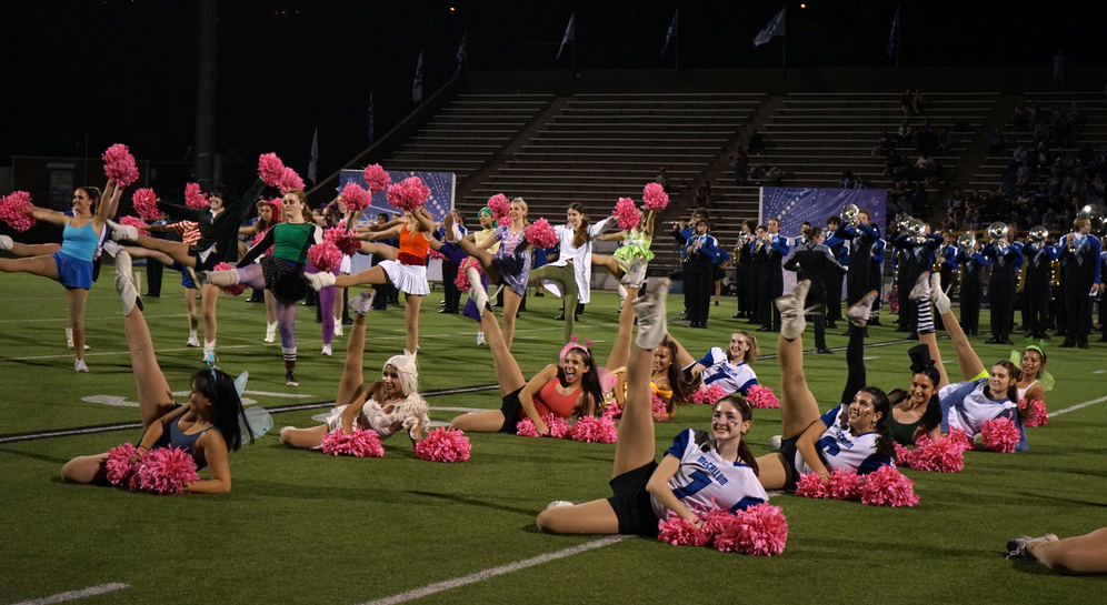 A NEW UNIFORM: Members of the Blue Brigade throw their legs in the air while performing during halftime at the annual Battle of the Bell. Senior team member Olivia Hexsel, the second dancer in the row on the right, said that while the game was memorable for its close score and the nerves she felt for her team, it was also fun to perform out of her typical game-day uniform. Since the game was the last one before Halloween, members of both cheer and Blue Brigade dressed up in costumes. Hexsel, a social officer, and the rest of her squad dressed up as football players. “[My squad leader] and I thought about doing football players because one: we wouldn’t have to spend money on a costume, two: it was comfortable, and three: we just liked the idea of being a football player for the night,” Hexsel said. Hexsel felt that performing out of her uniform was beneficial to not only her dancing but also the general atmosphere of the game. “[Wearing a costume] wasn’t as hot and felt more comfortable to dance on the field,” Hexsel said. “I loved having to take pictures before the game in our costumes. It was my favorite part.” While taking pictures in her costume may take the cake as Hexsel’s favorite part of the game, she also noted getting to ring the traditional bell to celebrate the Knights’ victory as a highlight. “For a moment there, I thought we would lose, but I’m glad the football team came out with a win,” Hexsel said. Caption by Lanie Sepehri.