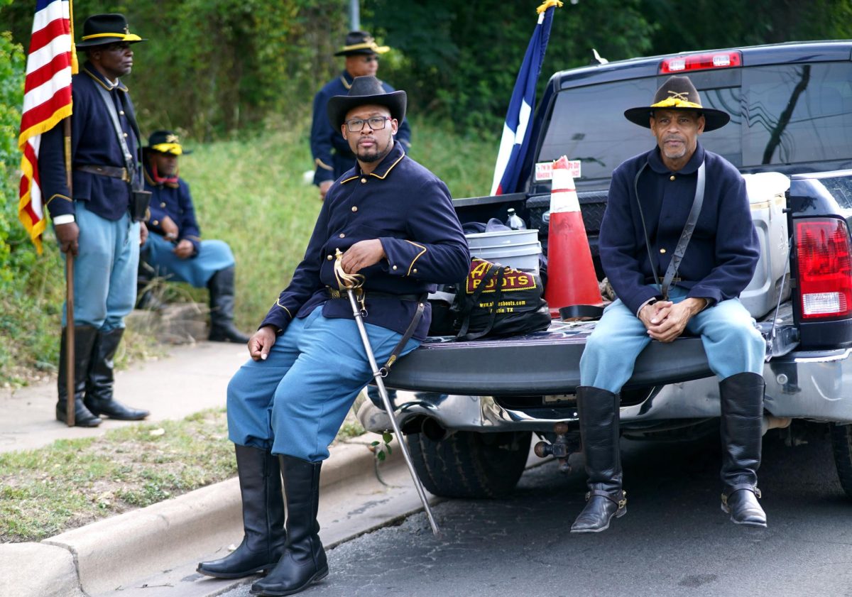 BUFFALO SOLDIERS: As part of a quintet of reenacting Buffalo Soldiers, two men sit on their truck taking in sights from the Central Texas Juneteenth parade while the other three reenactors observe from the sidewalk. The Buffalo Soldiers were regiments of African-American men who served in the western frontier with distinction following the American Civil War.