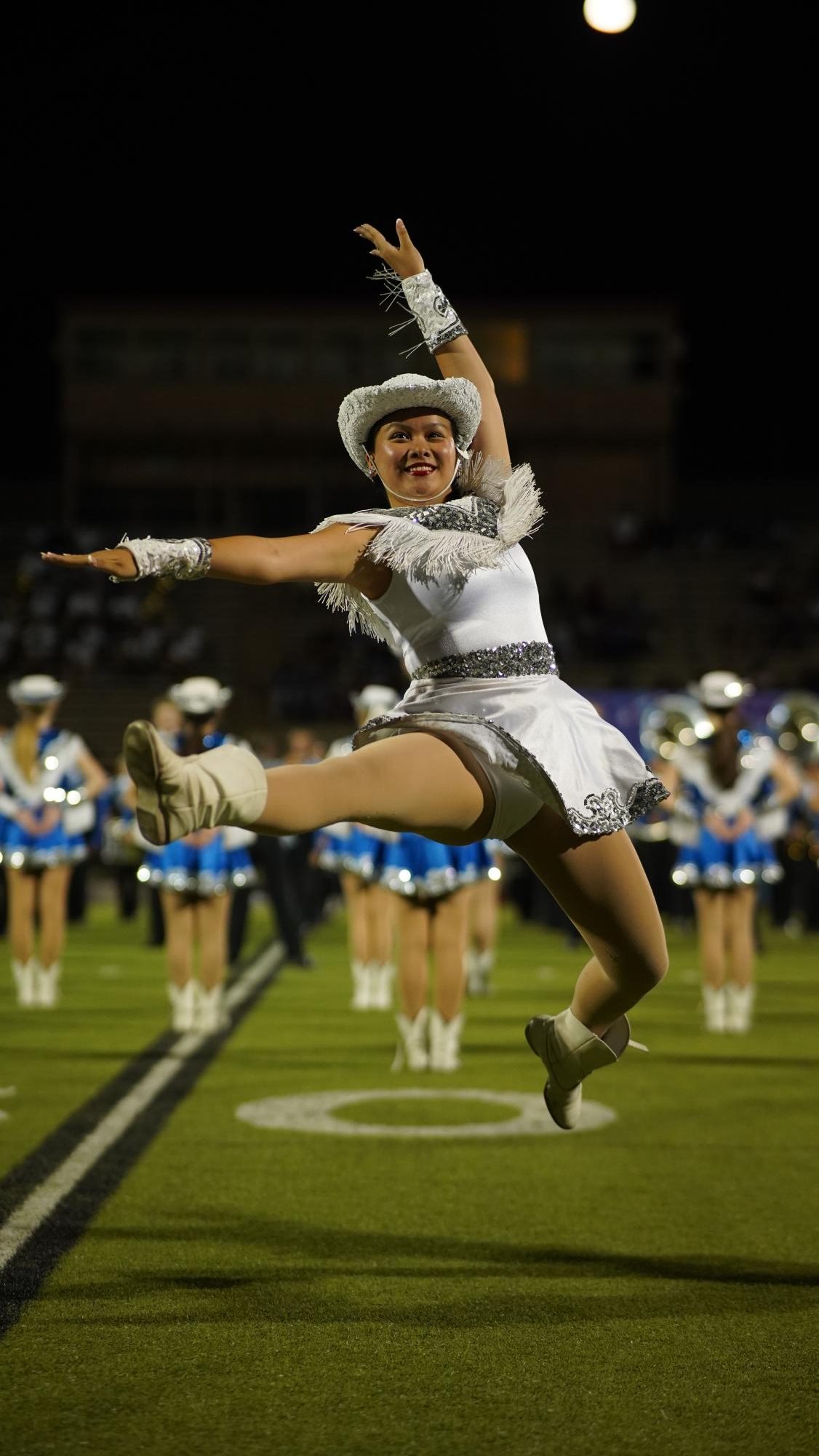 Blue Brigade co-captain Sophie Leung-Lieu leaps high off the House Park turf during during officer introductions prior to the Brigades performance to Build Me Up Buttercup at halftime of the Knights 32-14 loss to LBJ on Sept. 29.