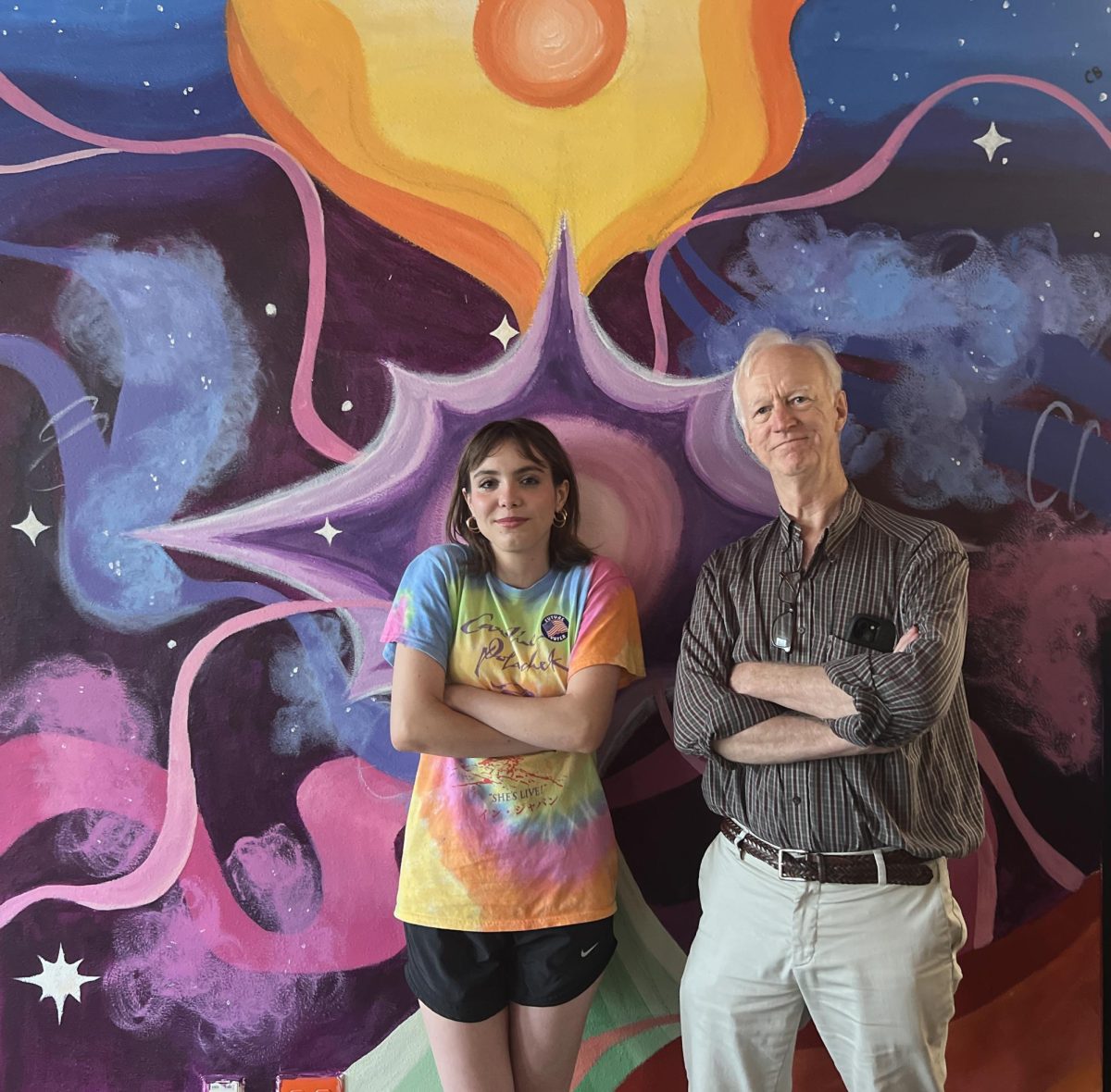 Sophomore Chim Becker and retiring math teacher Paul Pew pose in front of the library mural Becker created in Pew’s honor.