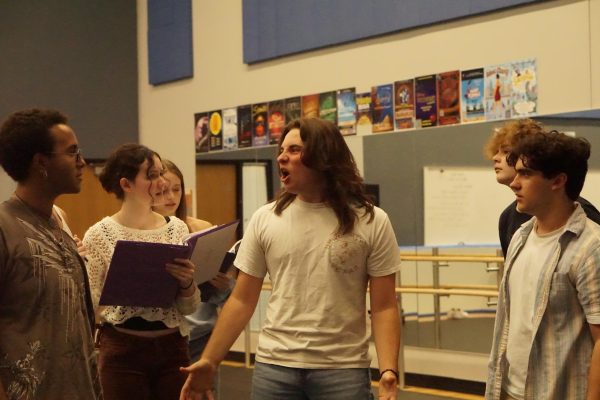 COLALEO IN THE YELLOW SUIT: Senior Joe Colaleo rehearses ferociously confronts the Tuck family about the water that turns people immortal as the cast of McCallum Theater’s fall production Tuck Everlasting blocks a scene. The rehearsal is for the actors to know where to be placed and stand throughout the show.

“I am feeling great about the process and creation of the show as a whole,” Colaleo said. “We are working really fast, we are super prepared. Everyone is working really hard, and we are just finishing up learning set traffic, cleaning and perfecting the show.”

In the show, Colaleo plays The Man in the Yellow Suit, a character he was hoping to get when auditioning. The character is greedy and selfish and his goal is to become wealthy by selling water from the spring in the woods.

“I want the water to sell for money and they are stopping me,” Colaleo said.

For Colaleo, Tuck Everlasting represents the start of his senior year and the final season with McCallum Theater.

“Playing this role as a senior is very fulfilling and fun,” Colaleo said. “Everyone looks up to you and you get a sense of accomplishment and pride when you see others doing well.”

Looking back on his four years in theater production, Colaleo said he wants to do everything he can this year to support the underclassmen and have fun in the rest of the shows this year.

“I really appreciate the process a lot more this year, knowing it will be one of the last times I’m doing something like this at McCallum and I won’t see a lot of these people for a long time,” Colaleo said.

Caption by Nate Williams.