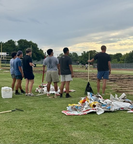 Coach Gammerdinger and several players survey their work on the field over this summer, moving one step closer to a grassy field