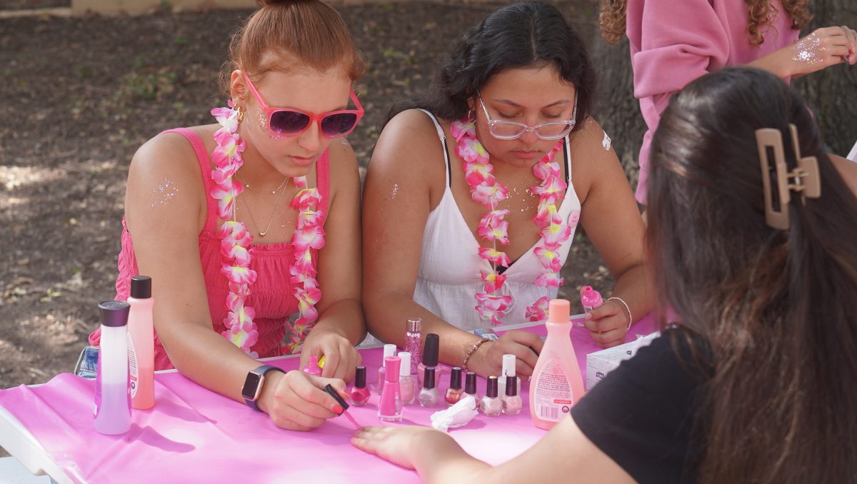 A POP OF PINK: PALS seniors Layla Al-Hallaq and Tabitha Briceño work the nail painting booth for Pink Week at lunch last Monday. Even though it is her last Pink Week, it was Briceño’s first year organizing the activities as a member of PALS. 
“It feels amazing knowing that I can finally contribute to Pink Week,”  Briceño said. “I have wanted this for a long time, and so finally participating in it has been truly fulfilling.”
Briceño claimed that her favorite part of the whole week was connecting with the other PALS, which she was able to do at the nail salon. 
“It [Pink Week] is a good way to connect with my classmates while contributing to something meaningful,” she said. “I loved being in the nail salon because I felt such a joy in painting nails and applying face glitter to get everyone pink-ified.”
Throughout the entire week, Briceño said she had mixed emotions.
“It was a bittersweet but exciting feeling as this was my first and last Pink Week in PALS,” she said. “I was just trying to soak it all up and live in the moment as much as possible.”

Caption by JoJo Barnard.
