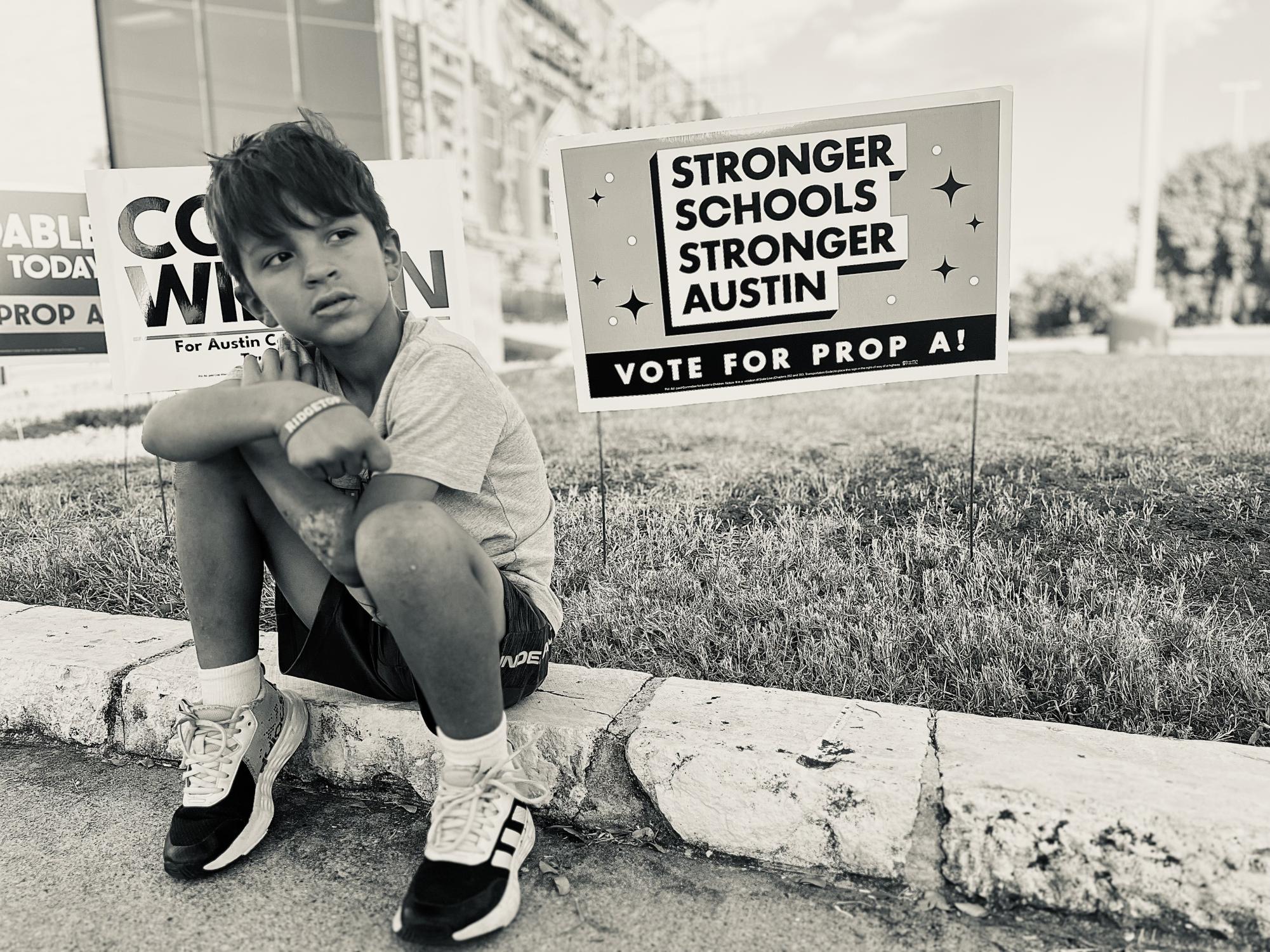 Ridgetop Elementary School first-grader Sebastian Celio sits outside the George Washington Carver branch of the Austin Public Library where his mother cast her early vote in the 2024 Travis County election. 