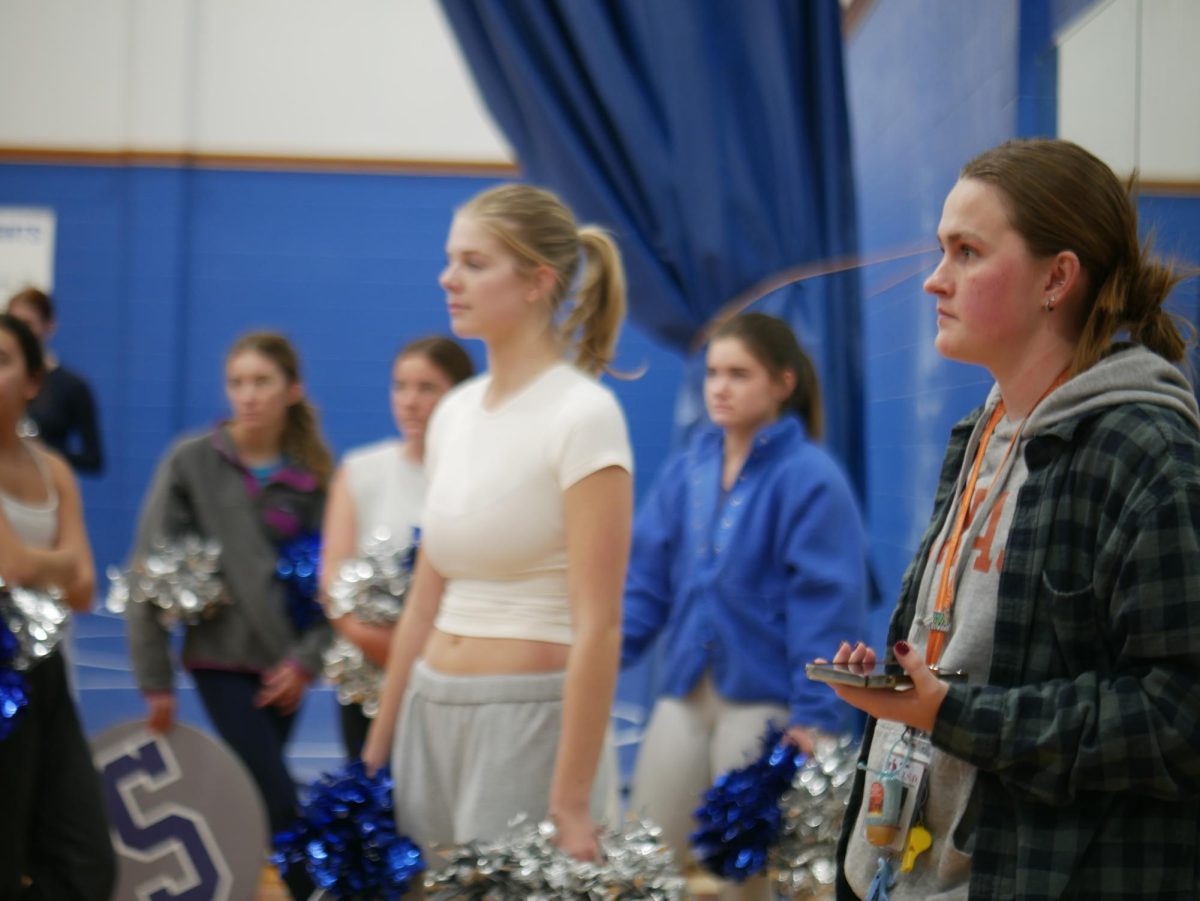 Cheer coach Sydney Shreiver watches as stunt groups warm up before practicing the UIL routine. 