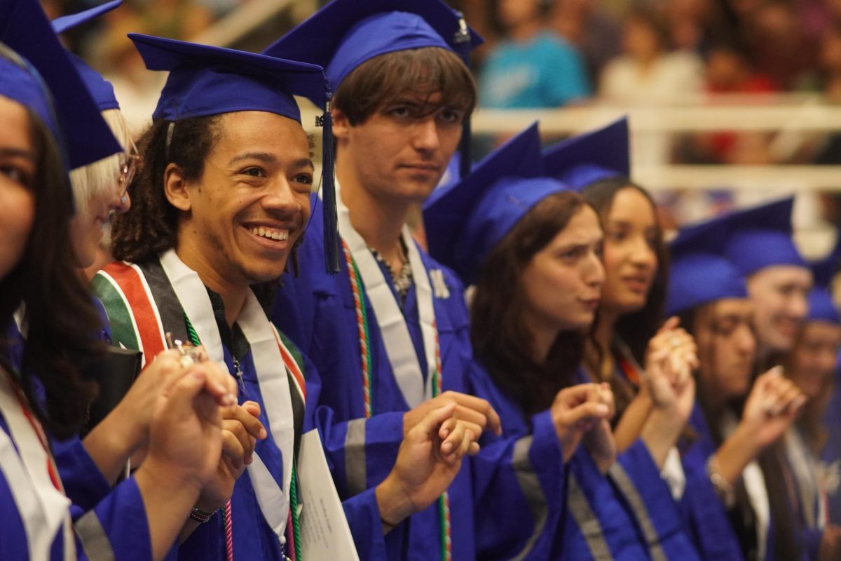 Class of 2024 graduate Jude Masoni smiles as he sings the school song one last time at graduation. The McCallum commencement ceremony took place on Thursday May 30 at the Burger Activity Center. After the class filed into the arena with pomp and circumstance, senior class president Hannah Herrera and student body president Olivia Hexsel led the Pledge of Allegiance and the Pledge to the Texas Flag. The band played the Star Spangled Banner, and the choir sang the Billy Joel classic, "And So it Goes." Speakers included District 4 Trustee Kathryn Whitley Chu, Superintendent Matias Segura, principal Andy Baxa, salutatorian Sadie Roselle and valedictorian Hannah Van Houten. Following the certification of graduates and the awarding of diplomas, the band played the school song and the graduates filed out into the unforgiving Texas heat, which did not seem to affect the collective mood in the slightest. Caption by Dave Winter. Photo by Julia Copas. 