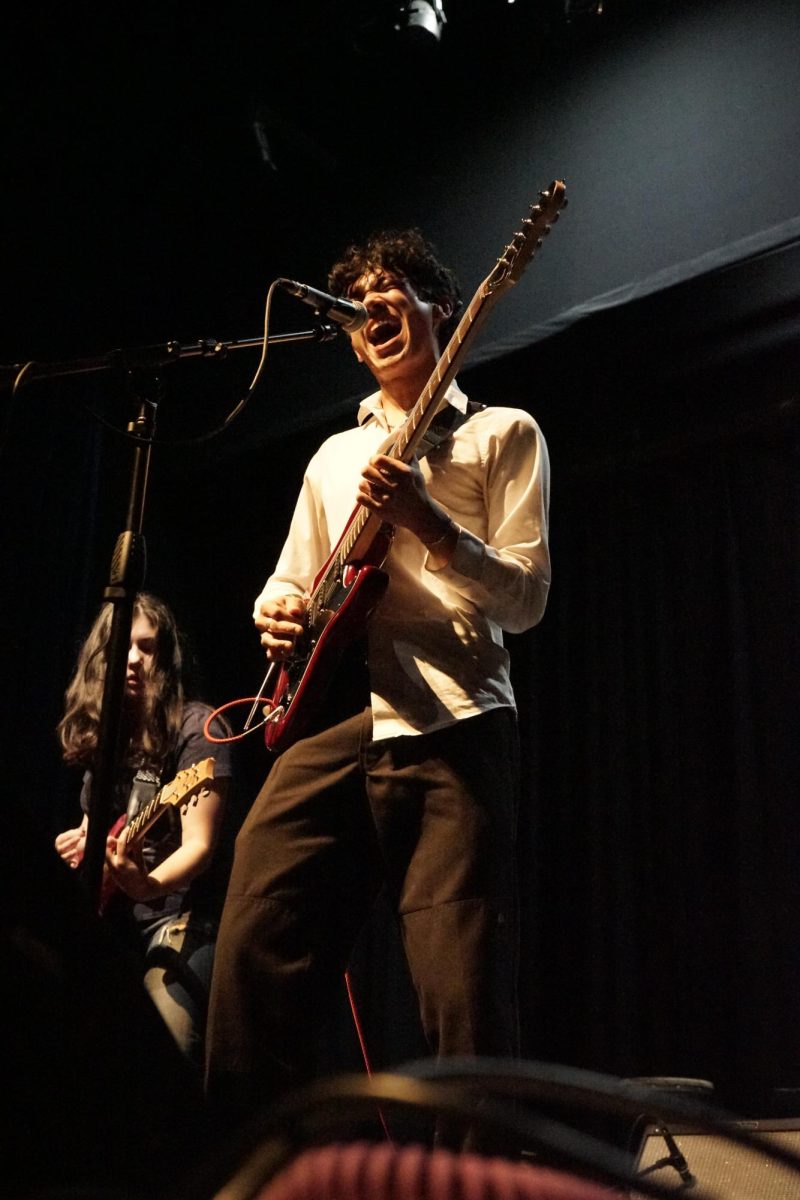 REACHING FOR THE STARS: Junior Zane Shieh sings an original song while playing the guitar with his band, Spiral Maze, at the Battle of the Bands last Thursday.

He sings the long note of his band’s original song entitled “Reach,” a part of a new album coming soon.

“This is my second year doing Battle of the Bands and with Spiral Maze,” Shieh said. “We had a pretty tight set, but I think it went really well, and the crowd liked us a good bit.”

Shieh said his excitement toward playing at the Battle of the Bands this year was being able to showcase his band’s new music.

“My favorite part was performing our new song, and playing for a bunch of my friends was super sick,” Shieh said. “It was stressful at first—like a little nervous—but it all cleared up right after the first song, and the atmosphere was very chill.”

While it was not his band’s first time performing in front of a crowd, Shieh said he loves playing music at his own school and performing original music.

“We’ve played at the Austin Rodeo two times and a few restaurants like Tamale House and Freddo’s ATX,” Shieh said.

Shieh and his band will be back performing at school at the upcoming first annual McCallum Art Party fundraiser on Feb. 22.
Caption by Nate Williams.