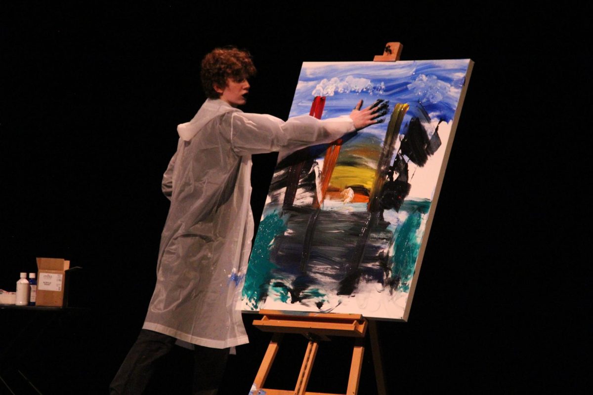 PAINTING POINTS: Junior Joseph Blackwood performs painting skit for Mr. McCallum pageant on Saturday night. Blackwood came in third for the entire competition after several wins throughout the week's challenges including his second place win for raising the most money in the ice bucket challenge.

As a fellow actor, sophomore Hallie Cooper was assigned to be Blackwood's guide througout the week, orienting him where to go and what to do for the various challenges.

At the end of the week, Blackwood was awarded third place after all his hard work earning points throughout the week from supporters and sponsors through all the various challenges as well as his final culminating performance on Saturday. 

Caption by Josie Mullan. Photo by Lillian Gray.
