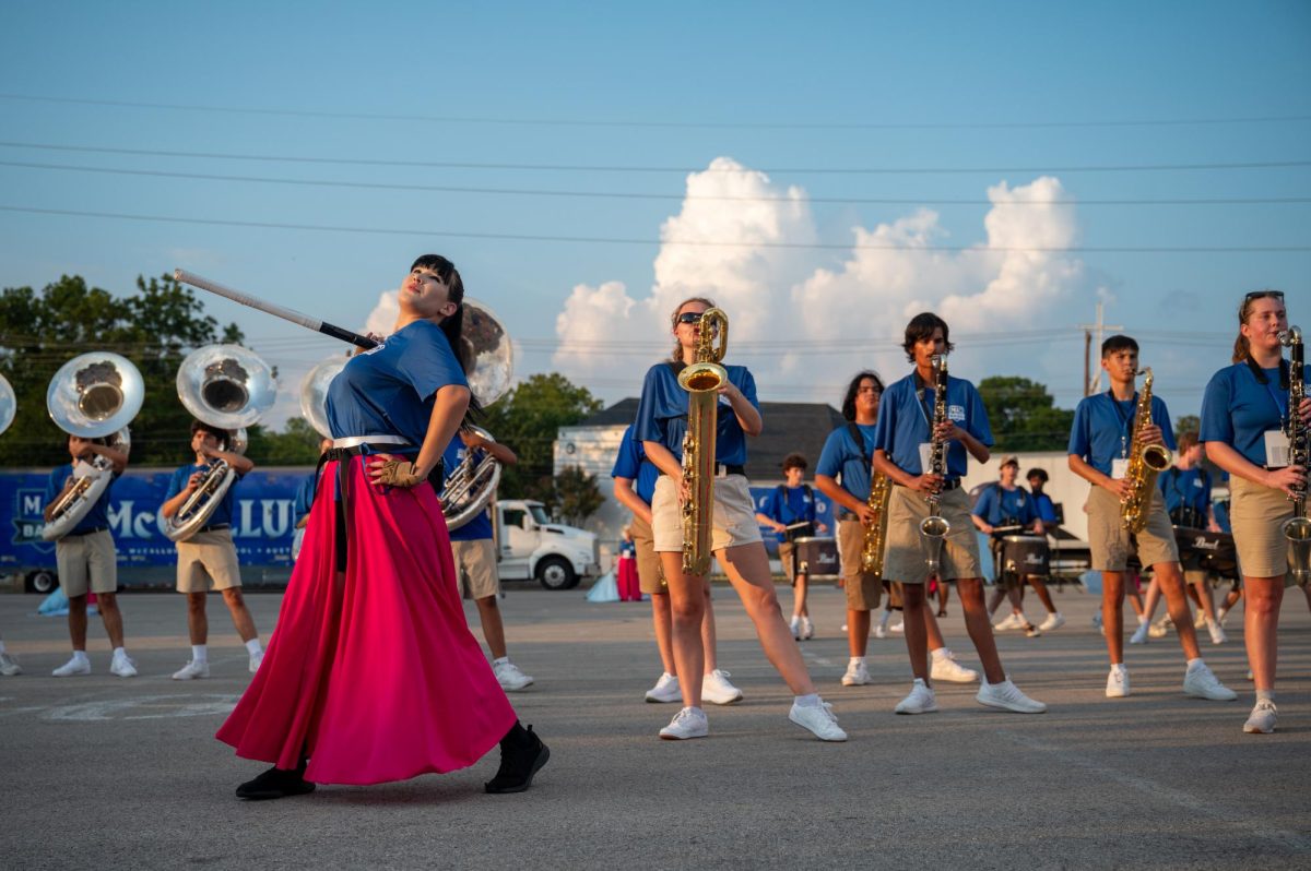 CLOSE-KNIT: Senior Alabaster Lippert twirls a prop gun during Color Guard’s routine at Bandapalooza Friday evening outside of the MAC. The performance gave Color Guard and Band an opportunity to debut their “Gothic Renaissance” themed show for the 2025-2026 season. 
Junior Aubrey Macedo, the flag leader of color guard, believes there were some environmental and timing challenges regarding choreography during the show. Despite the challenges, Macedo believes they will be able to improve this season. 
“We can have a great season, that we can improve our counting,” Macedo said. “And that we are able to walk off at our last show and be proud of the product that we have made.”
What makes this year extra special for Macedo is that it will be the last year with her senior friends. 
“One of my favorite things about this show is that it’s going to be my last one of my favorite people,” Macedo said. “I don’t think there’s anything more particularly special than that.”
Marching Band and Color Guard members attend many all-day competitions and football games throughout the year. The large amount of time spent together forged a bond according to Macedo.
“[The color guard] built a strong community,” Macedo said. “It’s more like a family because we’re always together.” 

