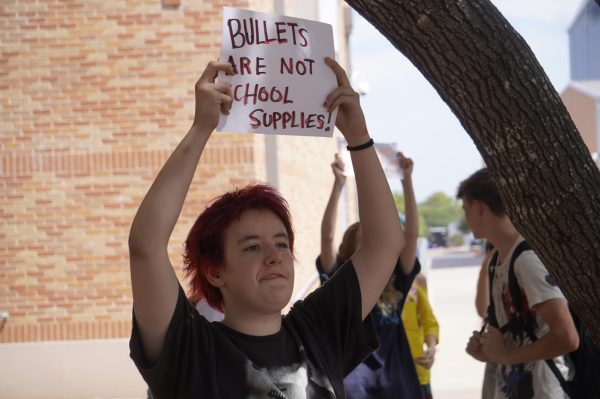 Senior Aristotle Balsimo holds up a sign reading "Bullets are not school supplies" to onlookers.