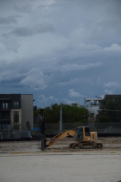 A bulldozer sprays water onto the field with a special attachment in the process of installing turf. 