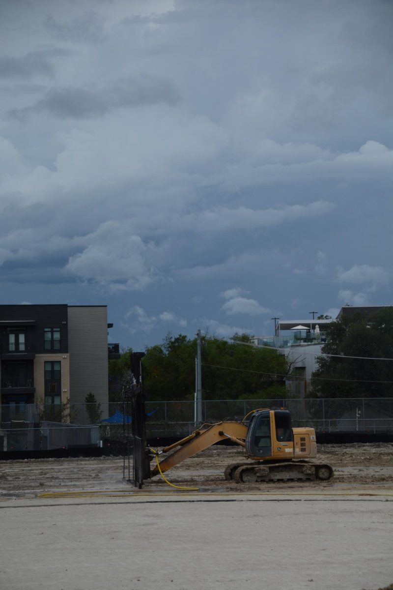 A bulldozer sprays water onto the field with a special attachment in the process of installing turf. 
