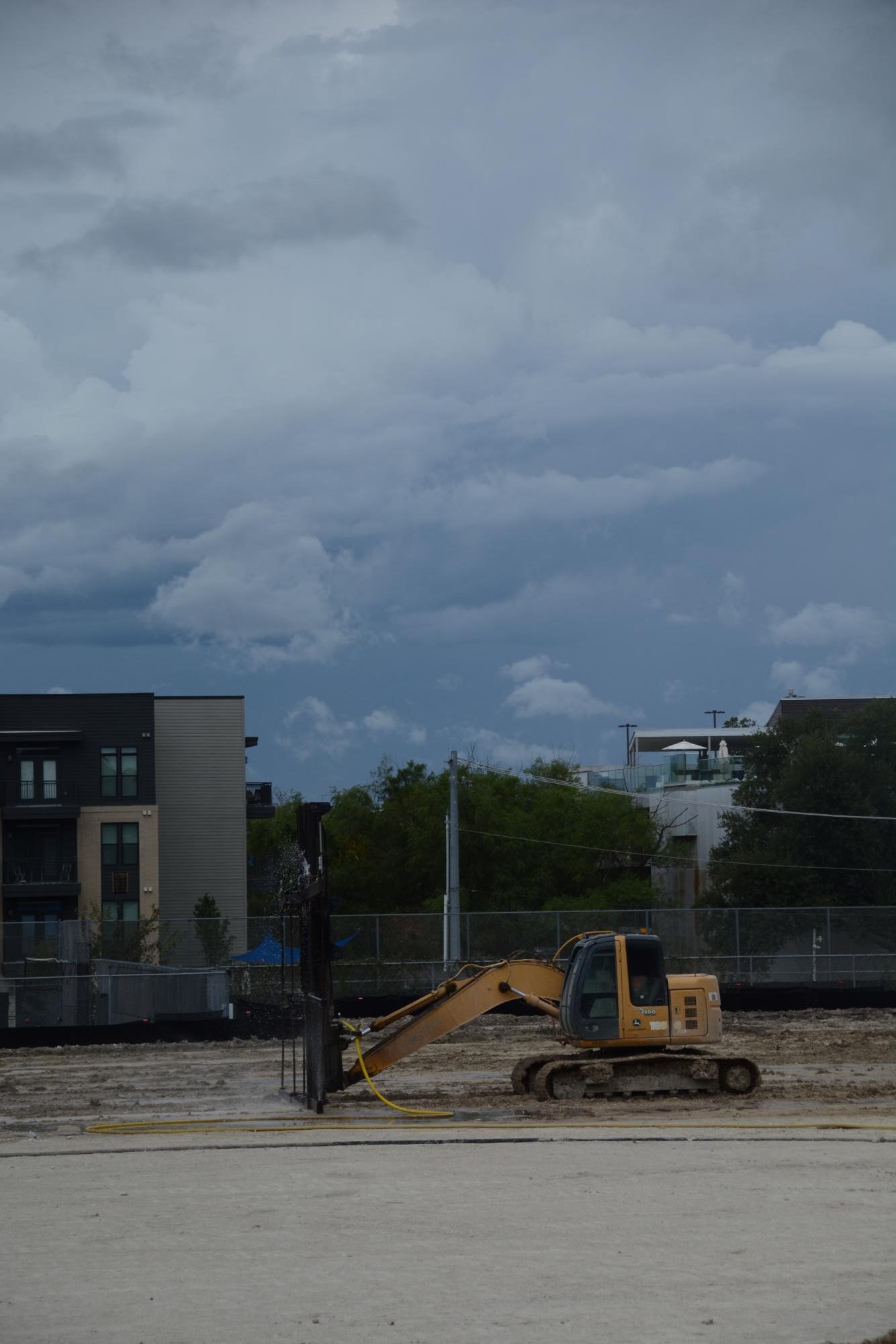A bulldozer sprays water onto the field with a special attachment in the process of installing turf. 