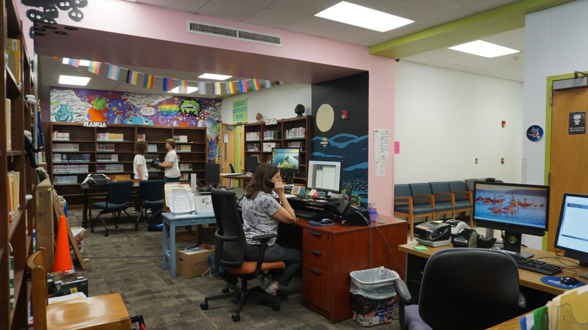 Front-desk receptionist Sara Zettner takes a phone call, while working in the temporary main office for McCallum.  Within the book shelves and art work, Zettner works to fulfill her daily tasks, while awaiting for the original office's completion. 