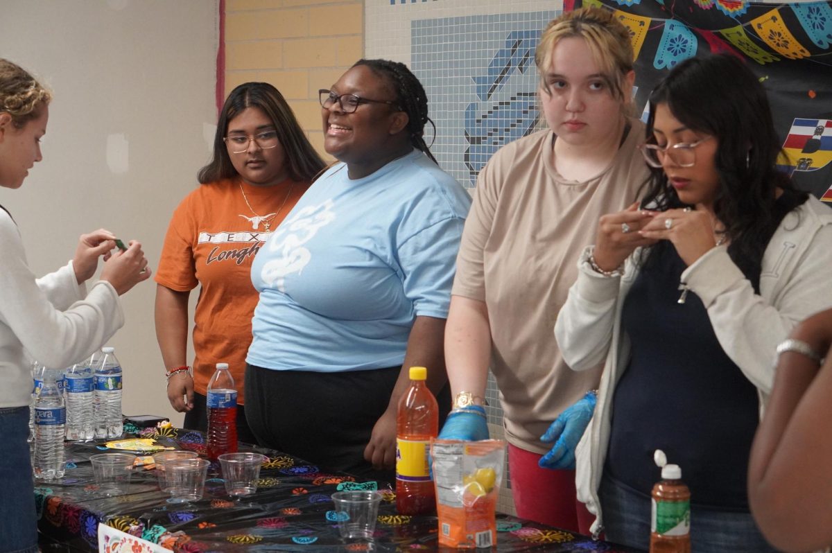 HELPING HANDS: Sophomore Paloma Ramon joined the Students of Color Alliance in the middle of last school year. SOCA was handing out agua frescas to students passing in the hallway, to spread awareness about the different cultures that should be celebrated throughout Hispanic Heritage Month.

“We do stands like those for Hispanic Heritage Month, Black History Month, and Asian and Pacific Islander Heritage Month.” Ramon said. 

The Students of Color Alliance gets all of their ingredients from local grocery stores like HEB and makes food from all the different cultures that they want to recognize. They then hand them out to students in the hallways to help other students learn about other cultures with these celebrated months. 

“We made salsa for the salsa contest, brought treats from different Hispanic cultures, and sold Hispanic candy.” 

In this stand, SOCA handed out agua frescas, which are a popular Mexican and Latin American drink made with a mix of fresh fruits, crushed flowers and seeds, and a sweetener.  

“I think that it’s important to celebrate all the Hispanic cultures because people often assume that everyone that is Hispanic is Mexican even though there are so many other Hispanic countries.” 

Caption by Piper Adair.
