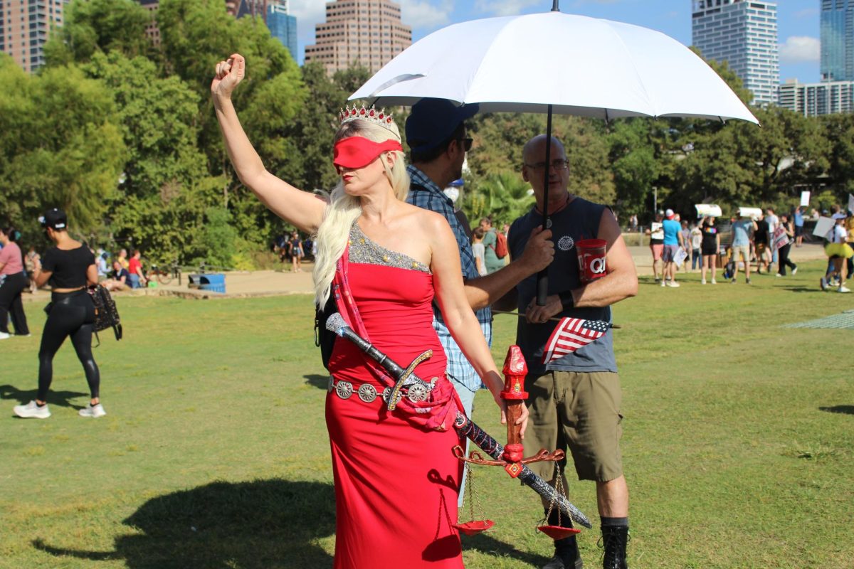 A protester dressed as Lady Justice raises her fist.