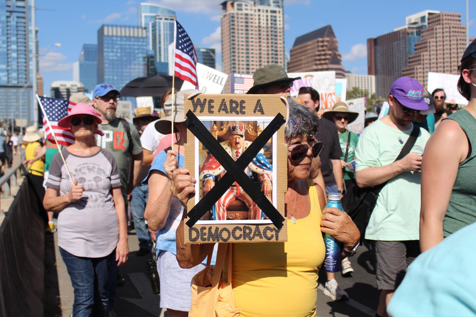 A protester holds up a pro-democracy, anti-monarchist sign.
