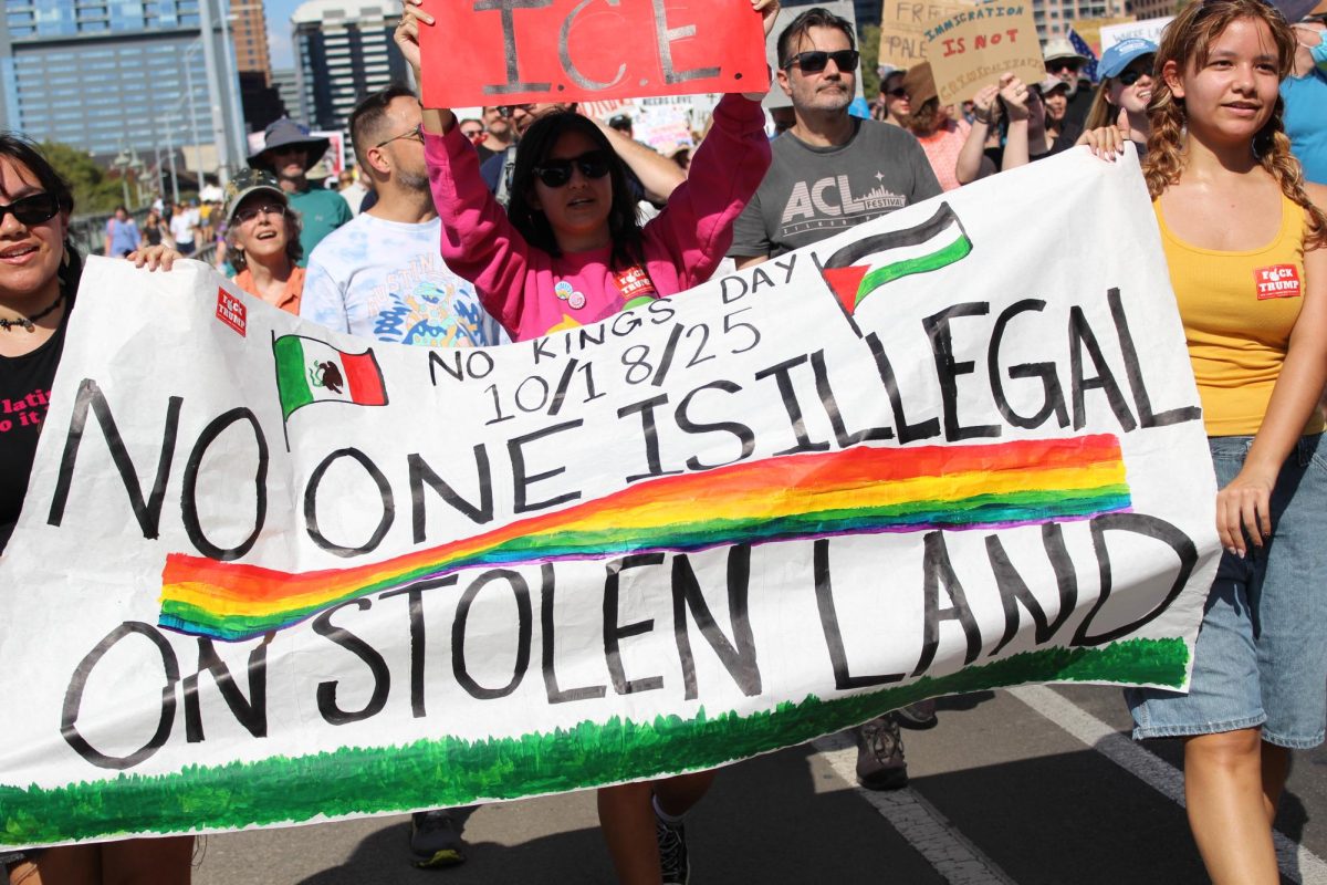 Protesters hold up a sign advocating against the displacement of indigenous peoples and hostility towards undocumented immigrants.