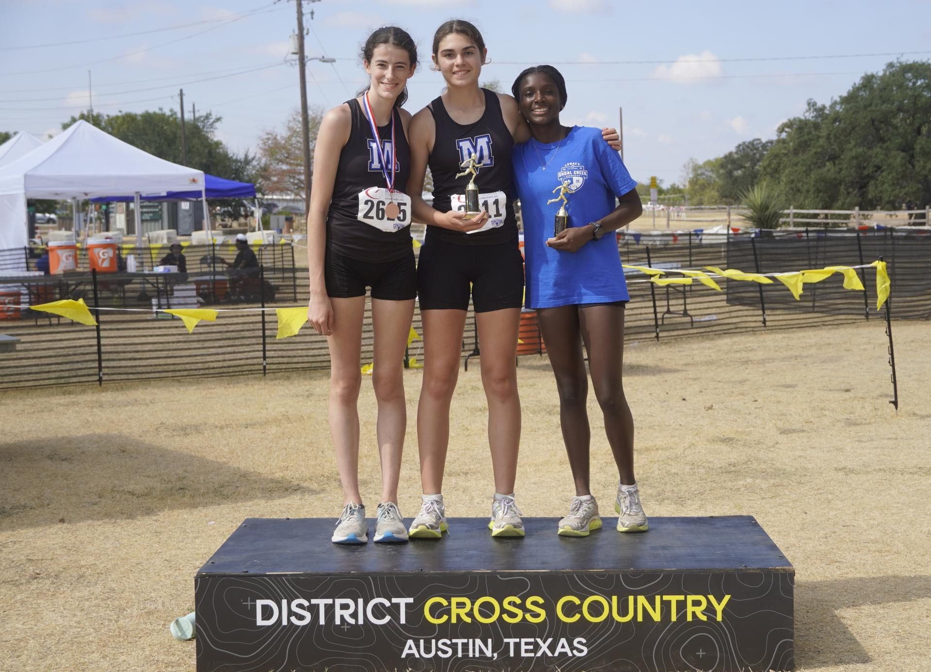 Senior Julia Lentz, sophomore Daisy Masters, and freshman Lila Goldberg pose for a photo with their awards at the District Cross Country meet on Oct. 9. Lentz and Goldberg both ran for varsity, placing top ten and advancing to Regionals, while Masters placed first for junior varsity, ending her season on a high note.