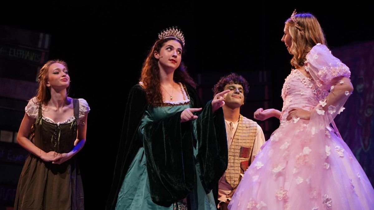 PUTTING ON A SHOW: Juniors Elora Clarke and Finley McBride and Senior Eleanor Pringle Rodney converse as their respective characters in the show “Between the Lines”. Clarke said the moment was funny, as it involved making fun of her fellow actor.

“In that scene, my character is talking about how she is going to make a baby with Prince Oliver,” Clarke said. “She thinks babies come from baby powder, so we’re all making fun of her.”

Clarke said her favorite part of the show was watching her fellow castmates perform.

“I loved the song ‘Out of Character’ because I got to watch all the wonderful dancers,” Clarke said.

Clarke said that dedication and commitment to the show had come to fruition.

“It takes a lot of time and energy to put on a show,” Clarke said. “You have to make a huge time commitment, but I think it went super well. We pulled it together greatly, the whole cast is talented and hardworking, and we did a phenomenal job.

Caption by Fletcher Vandegrift. 
