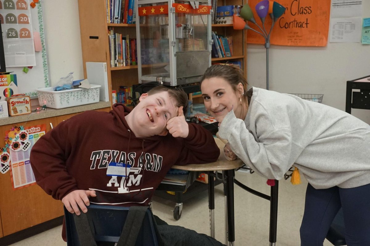 Life skills student Jaxon May and junior Lila Chilton pose during the Best Buddies Winter potluck Dec. 11. 