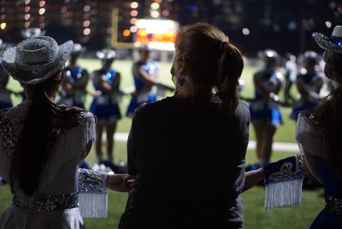 Searle joins hands with the 2021 Blue Brigade team in September at the football game against Connally.