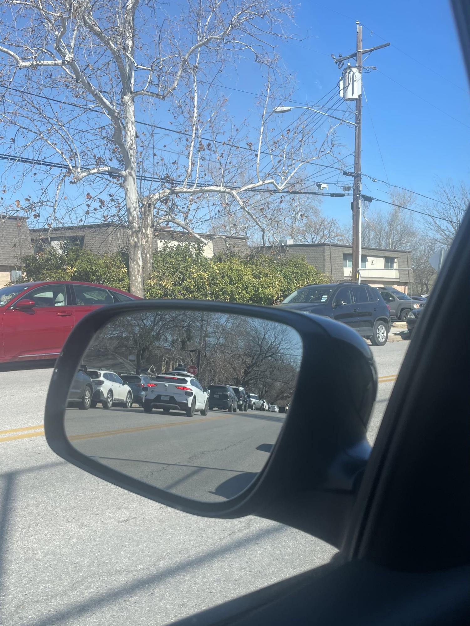 A Waymo passes parked students on Grover Ave.