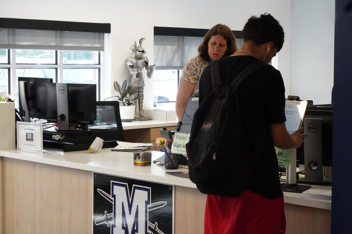 Student signing into the new office, aside front office receptionist Sara Zettner.